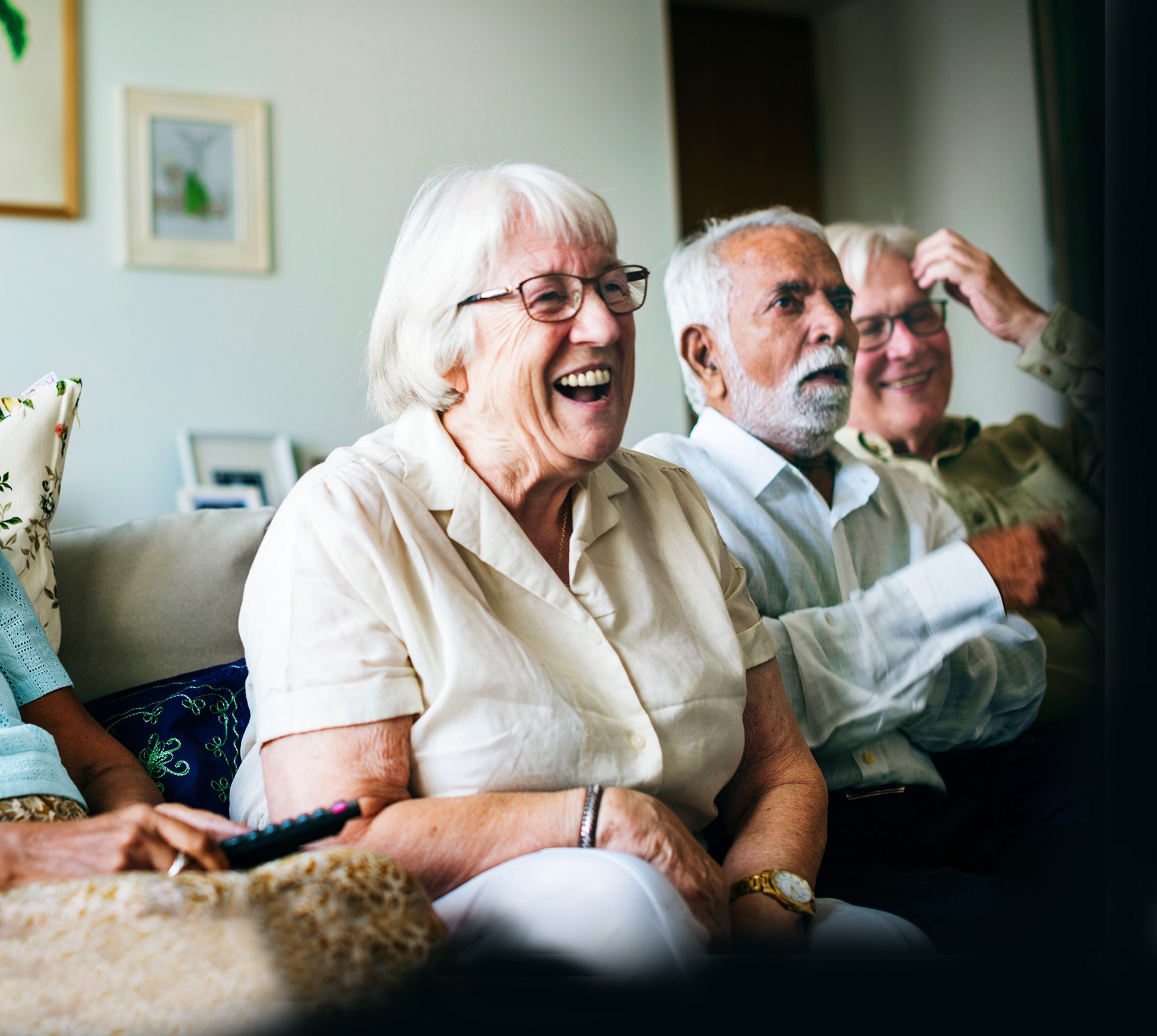 Pensioner in home laughing with others watching TV